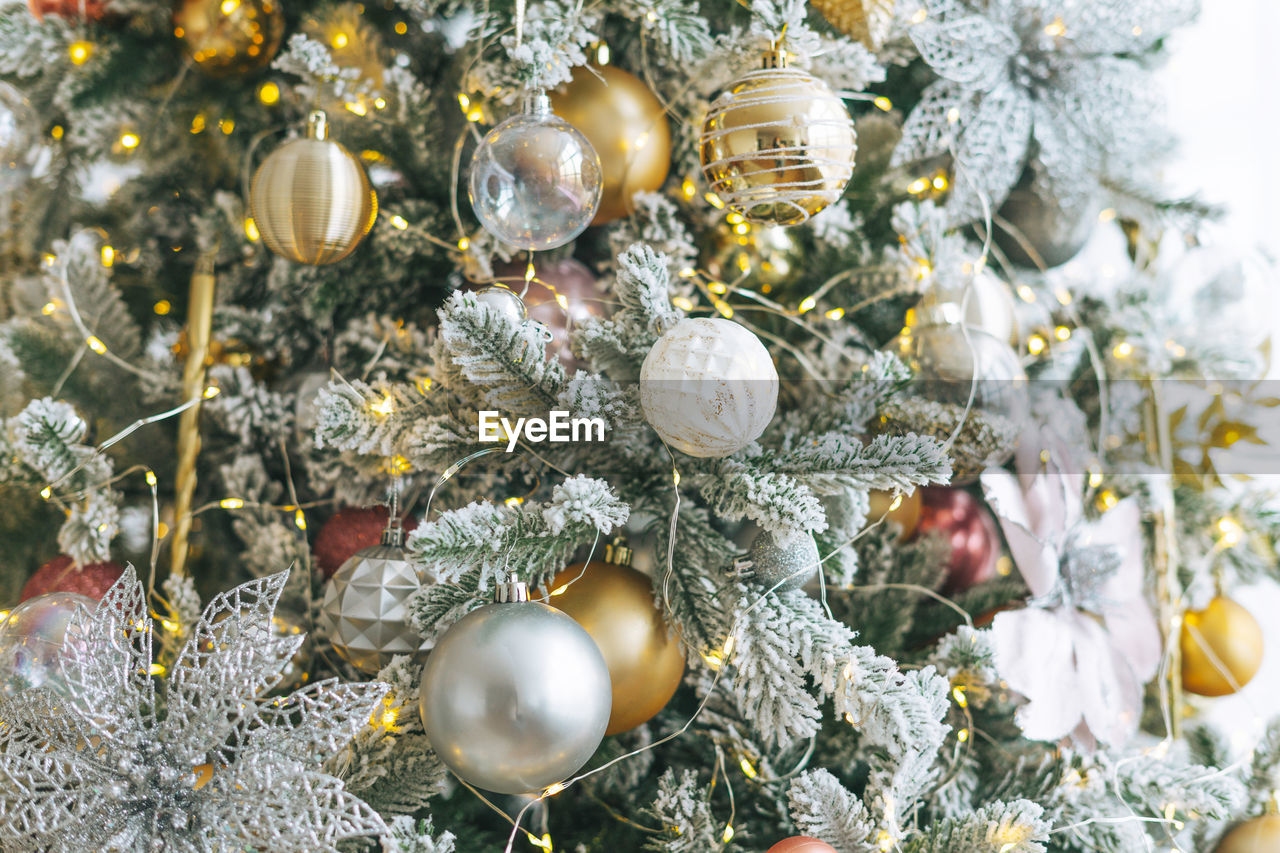 Decorated christmas tree in golden and white toys with the lights bokeh textured background