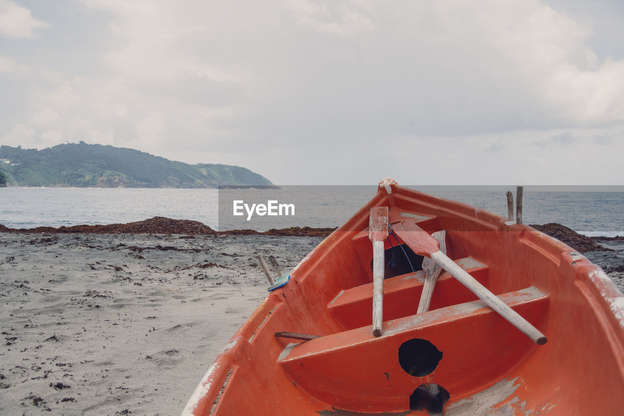 BOAT MOORED ON SHORE AGAINST SKY