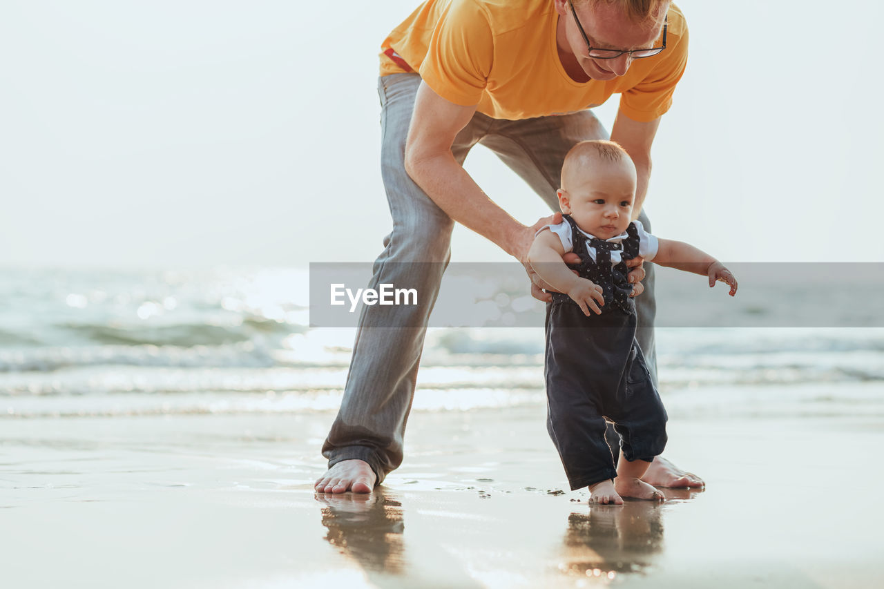 Full length of father and son at sea shore