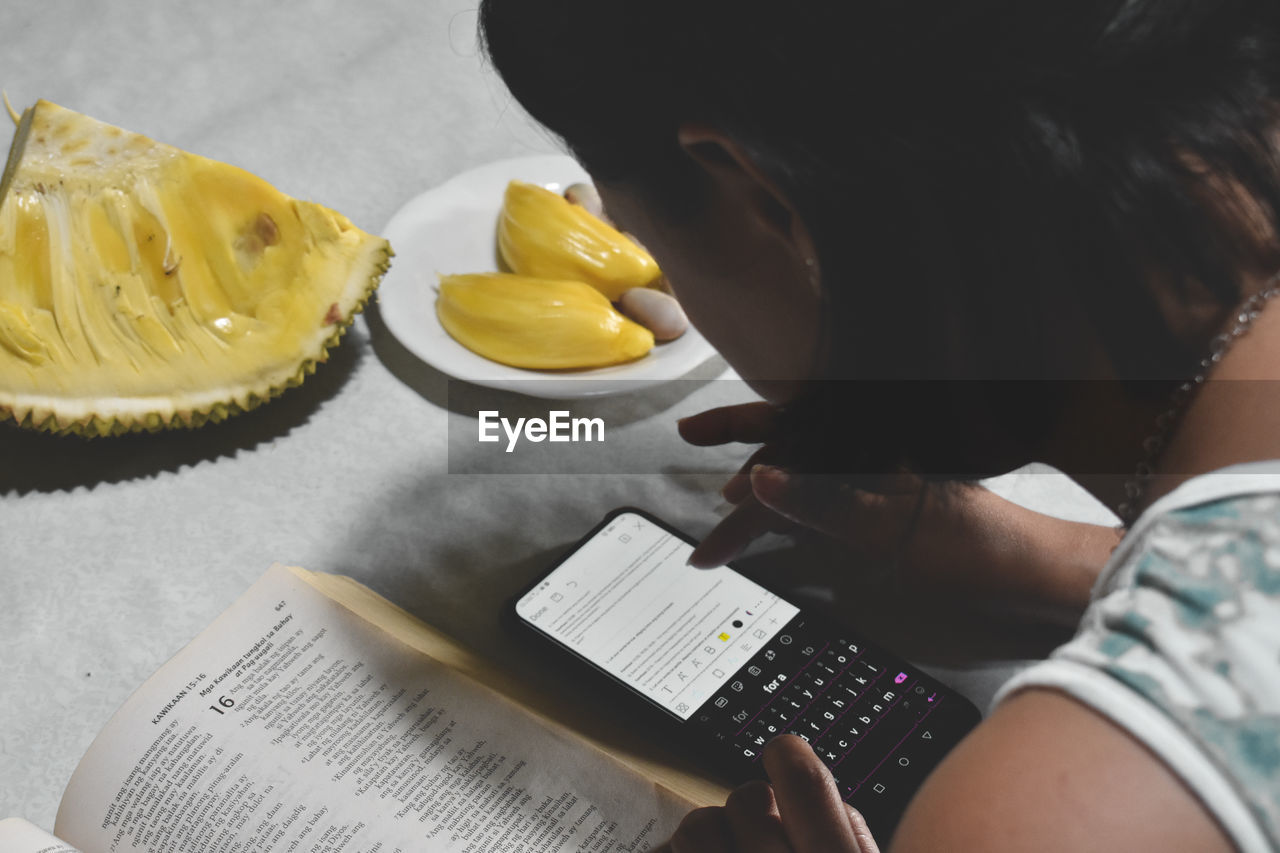 HIGH ANGLE VIEW OF WOMAN HOLDING BOOK WITH TEXT