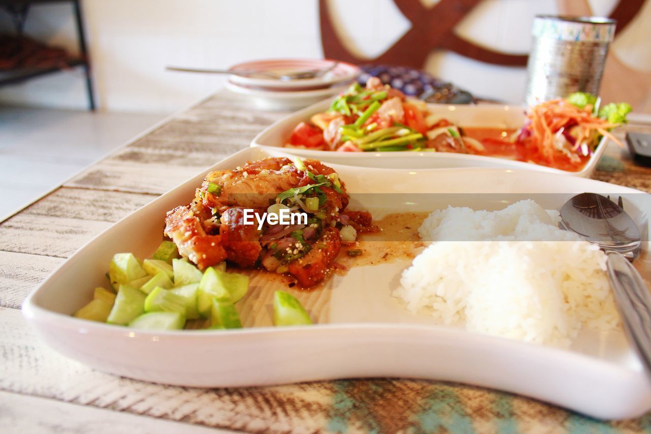 Meal served in plate by salad on table