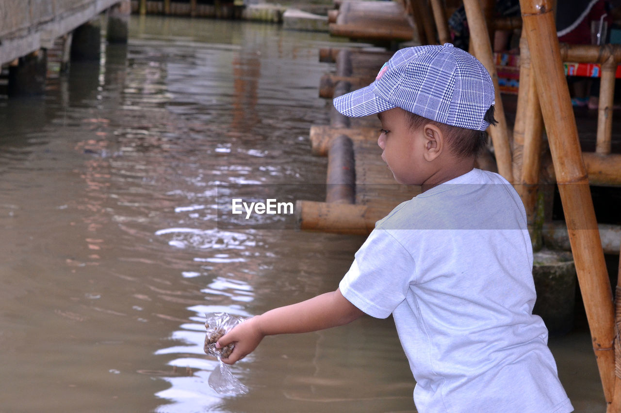 Boy feeding fish in pond