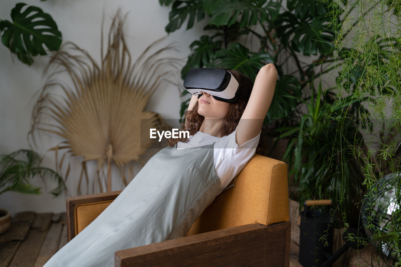 Amazed young woman using vr in home garden, resting in relaxing virtual environment. cyberspace.