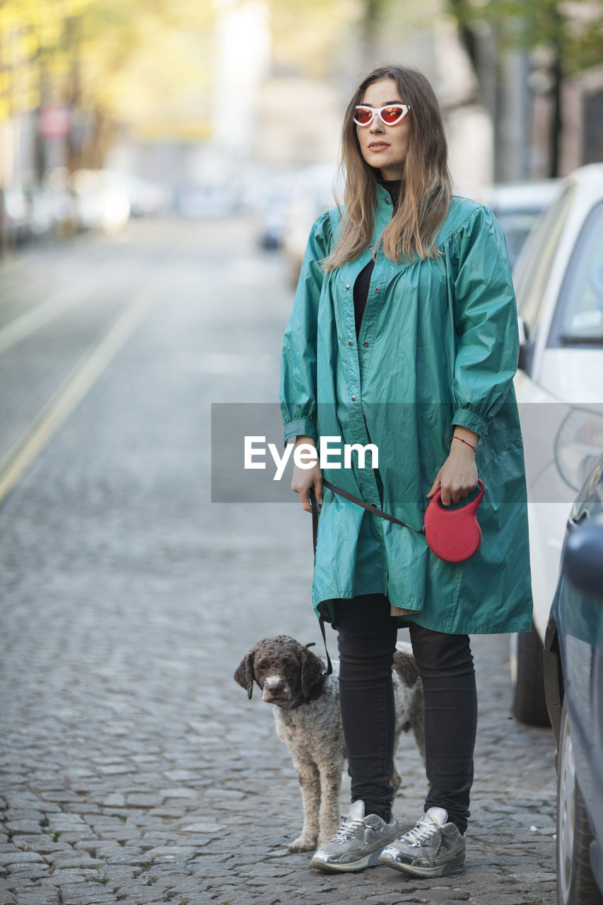 Smiling woman standing with dog on street in city