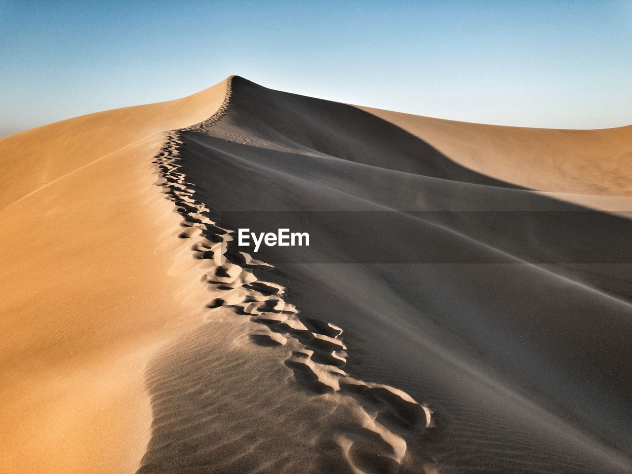 Sand dunes in desert against clear sky