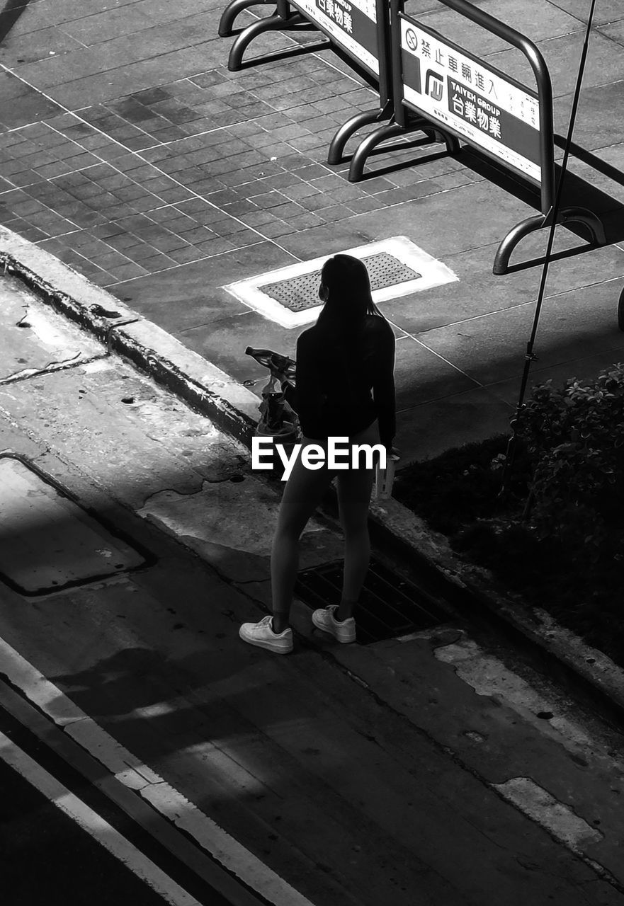 black, white, black and white, full length, monochrome, one person, monochrome photography, lifestyles, day, rear view, darkness, high angle view, road, sign, leisure activity, women, street, transportation, adult, standing, footpath, outdoors, men, casual clothing, person, city, architecture, light, nature, walking, shadow, communication, railing, sunlight