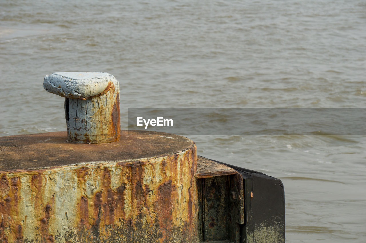 CLOSE-UP OF OLD WOODEN POST ON SEA