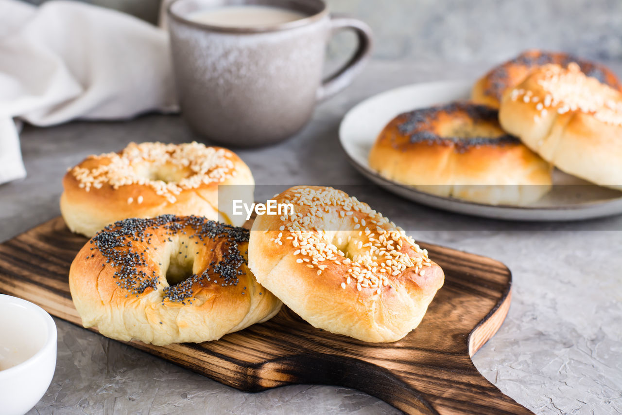 Bagels with poppy seeds and sesame seeds on a plate and a cup of coffee on the table. 