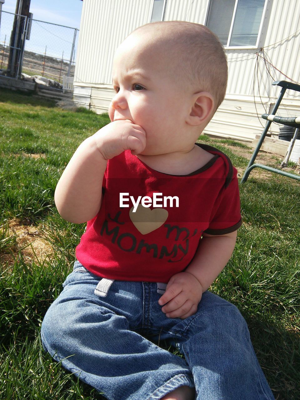 Cute baby looking away while sitting on grassy field