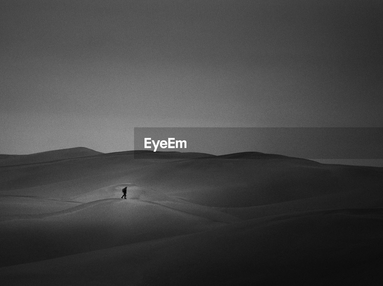 Man walking in desert against sky at dusk