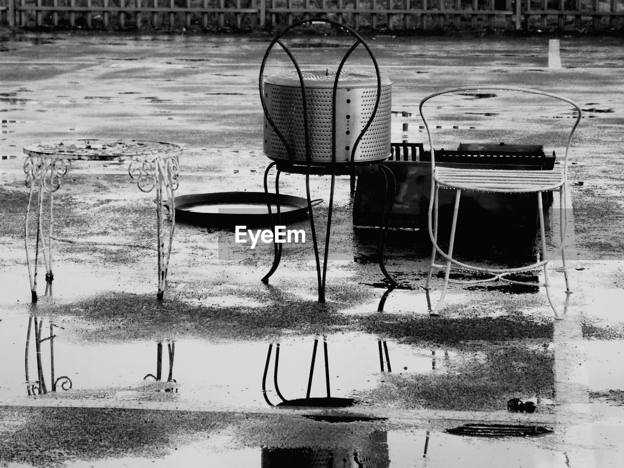 EMPTY CHAIRS AND TABLE ON WET FOOTPATH