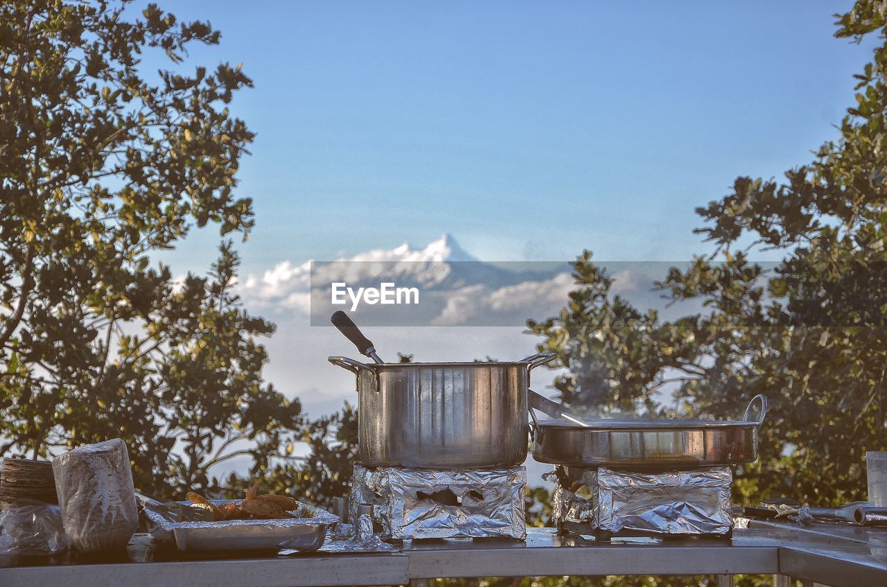 Cooking utensils on stove at table against sky