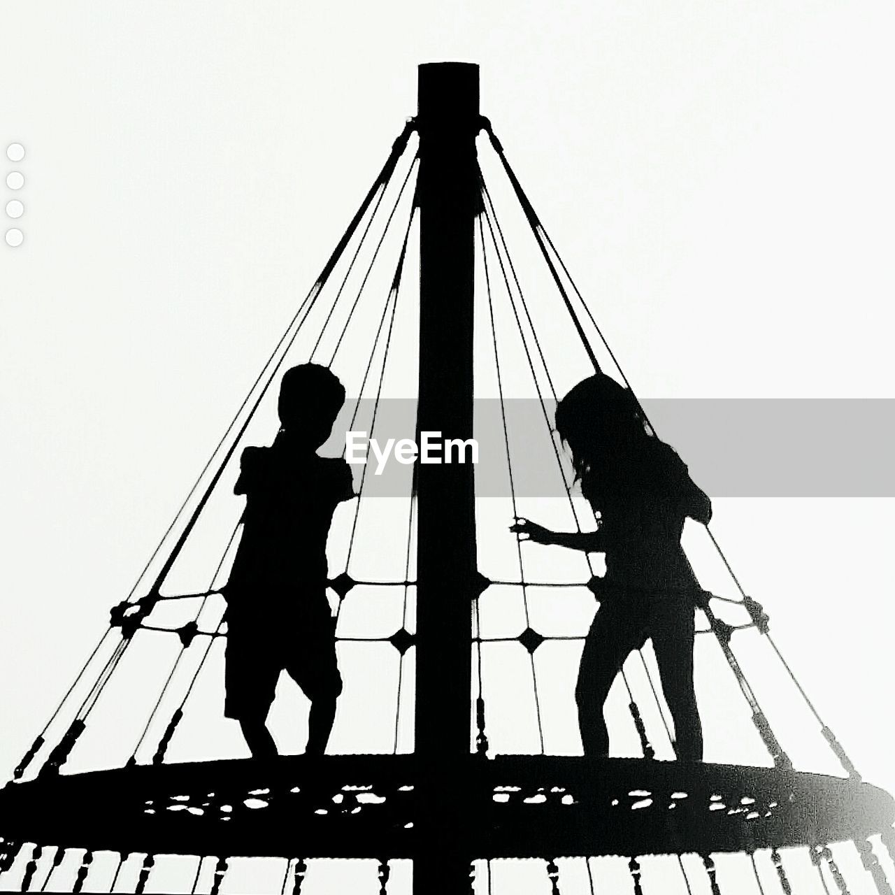 Two silhouette kids on ride against clear sky