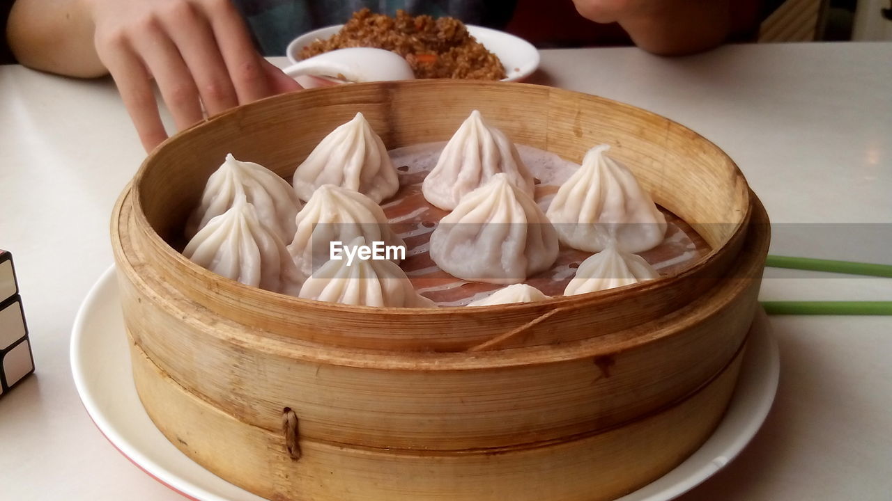 Midsection of person by dim sum on table