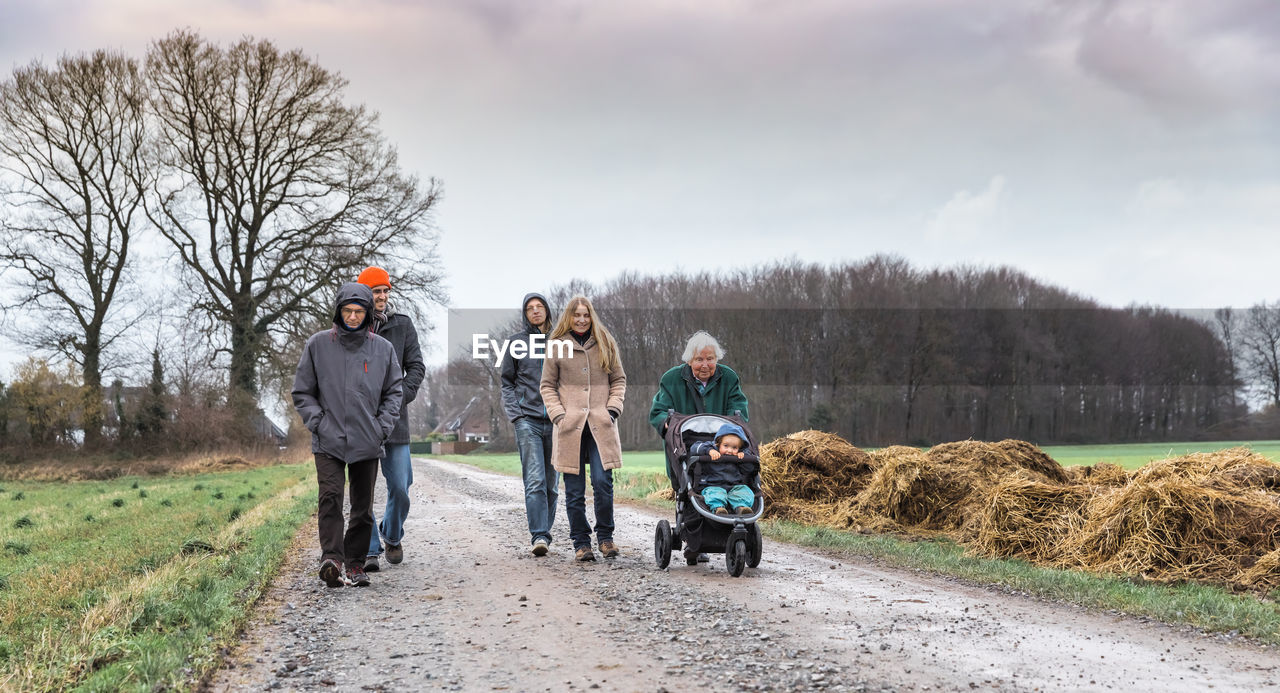 Family walking amidst field on road