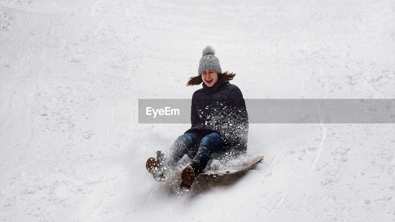 Full length of woman sledding on snow covered field