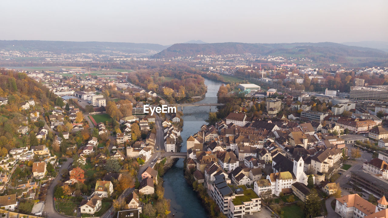 HIGH ANGLE VIEW OF TOWNSCAPE AND RIVER AGAINST SKY