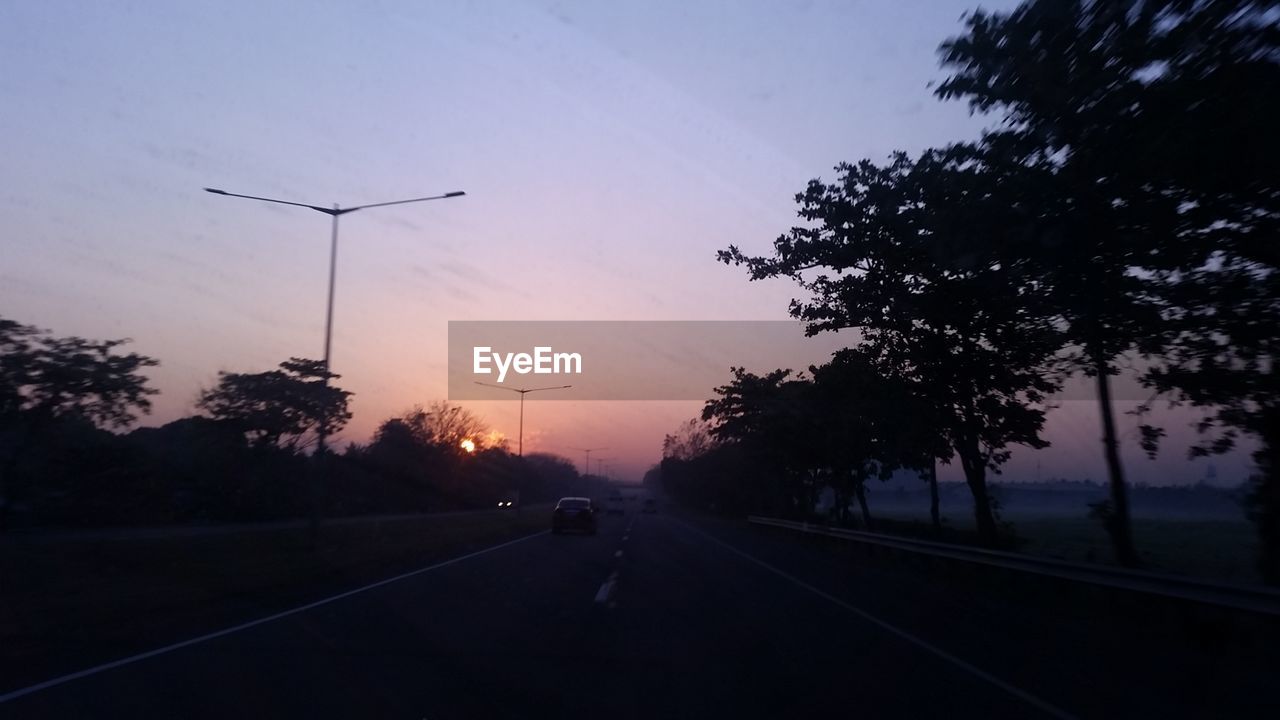 CARS ON STREET AGAINST SKY DURING SUNSET