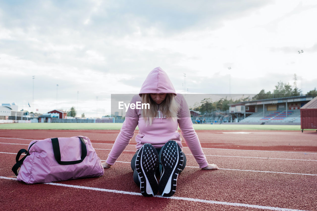 Woman sat on a running track looking nervous