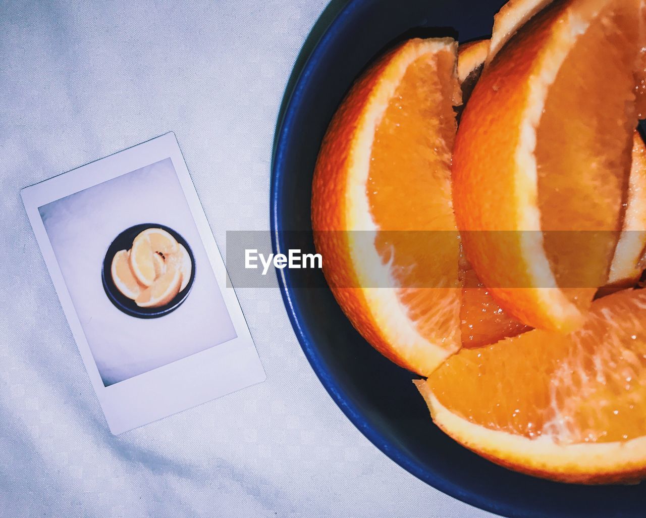 High angle view of sliced oranges in bowl with instant print transfer on table