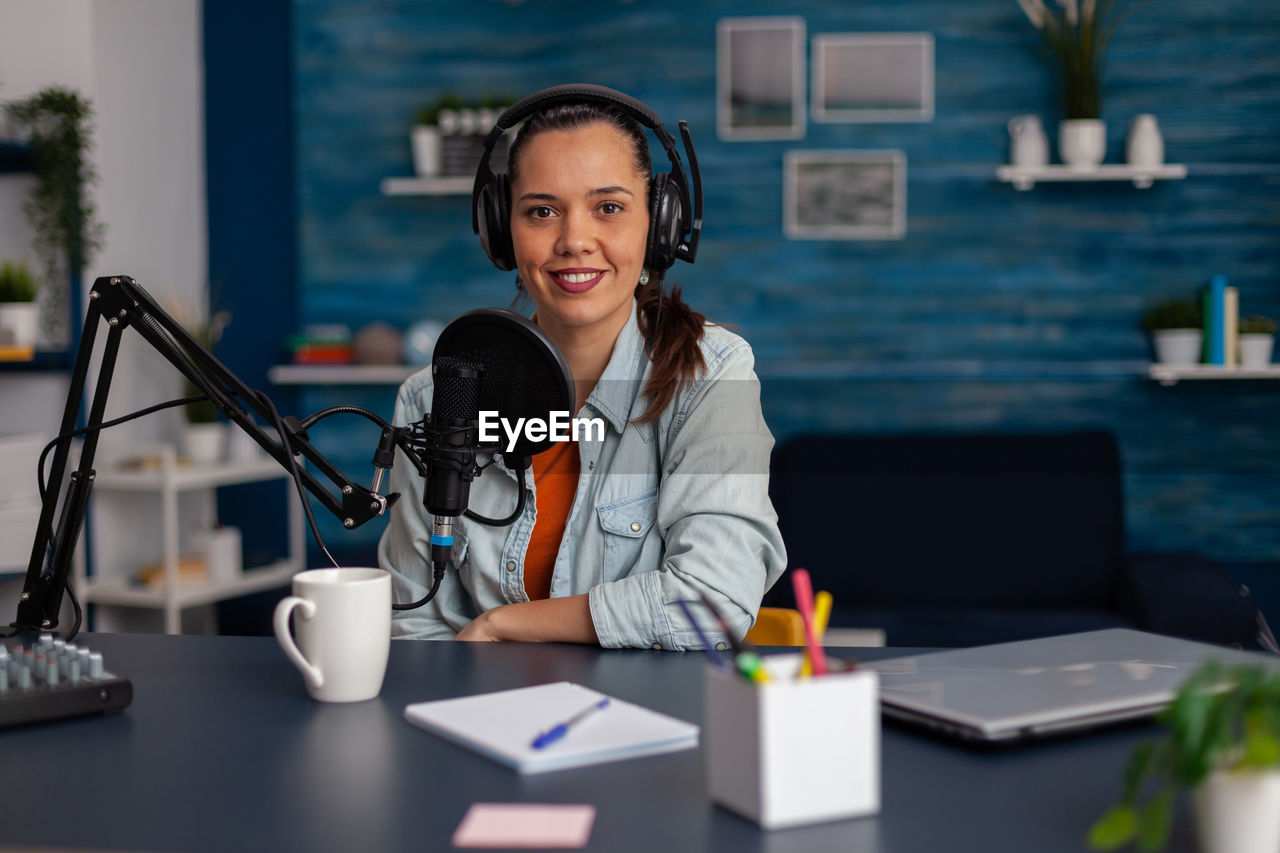 Woman wearing headphones doing podcast in office