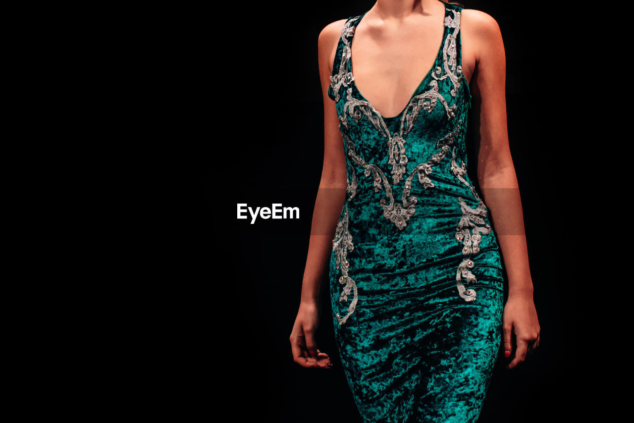 Green velvet evening dress on a female figure on a black background. feminine fashion clothes