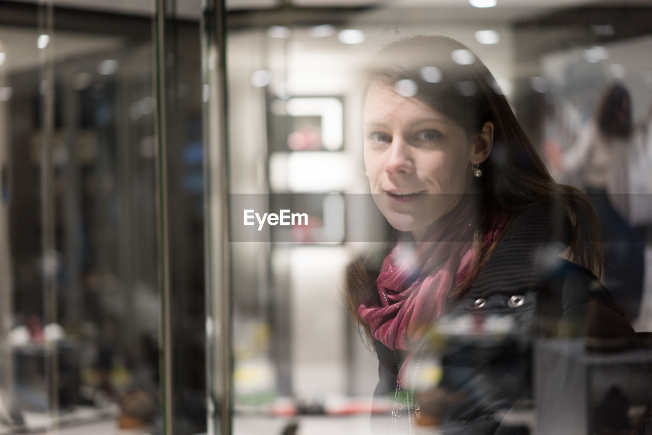 Portrait of woman reflecting on store window at night