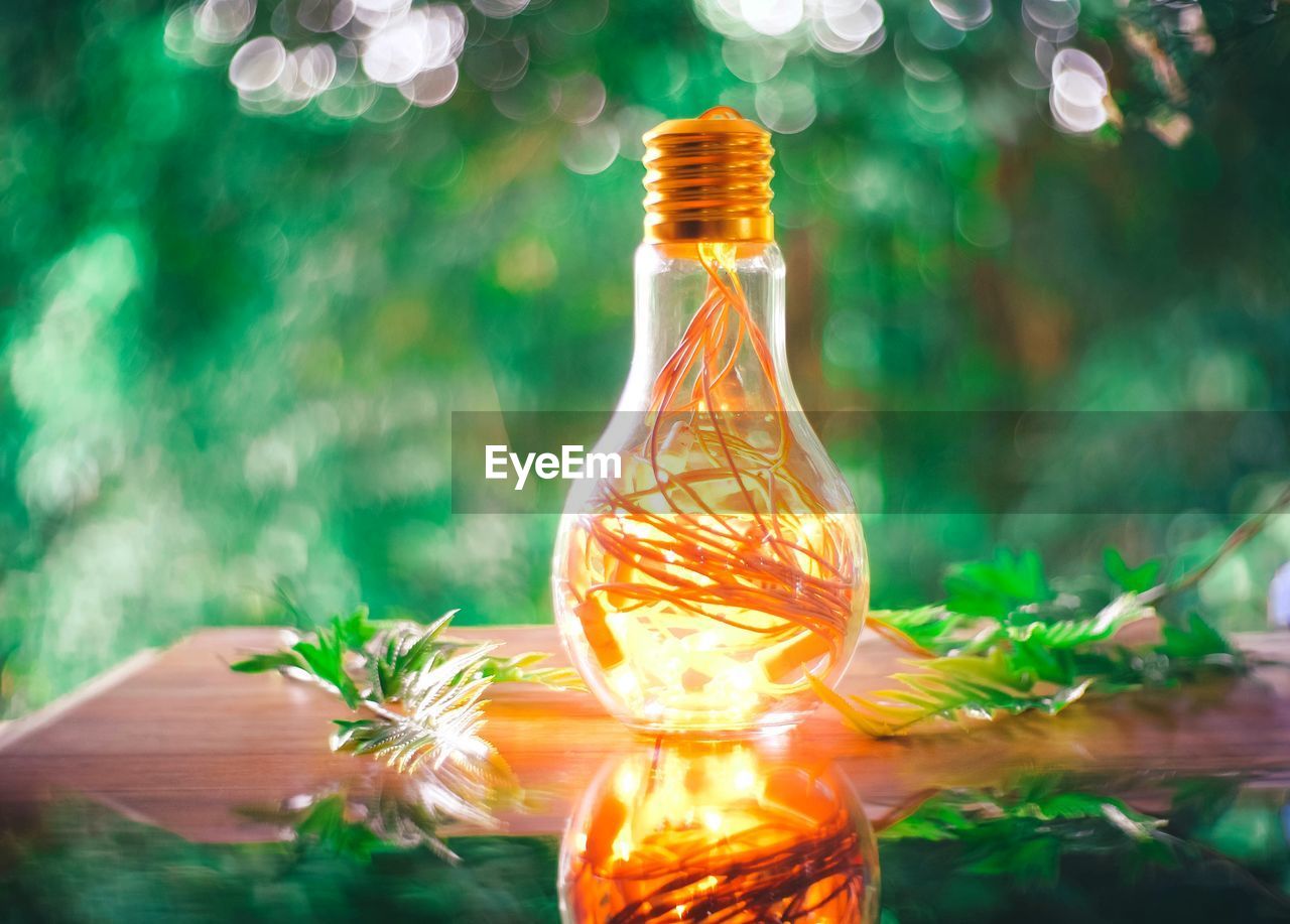 CLOSE-UP OF ILLUMINATED LIGHT BULB ON GLASS