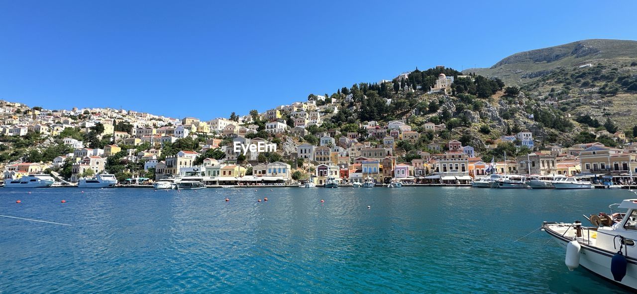 water, architecture, sea, sky, vacation, building exterior, nature, clear sky, land, city, built structure, building, travel destinations, blue, transportation, nautical vessel, mountain, harbor, travel, sunny, bay, coast, marina, no people, ship, day, residential district, waterfront, town, house, scenics - nature, mode of transportation, beach, tourism, beauty in nature, vehicle, yacht, outdoors, coastline, landscape, environment, sunlight, tree, moored, body of water, trip, tranquility, holiday, cityscape, summer, idyllic, bay of water, village, dock, community