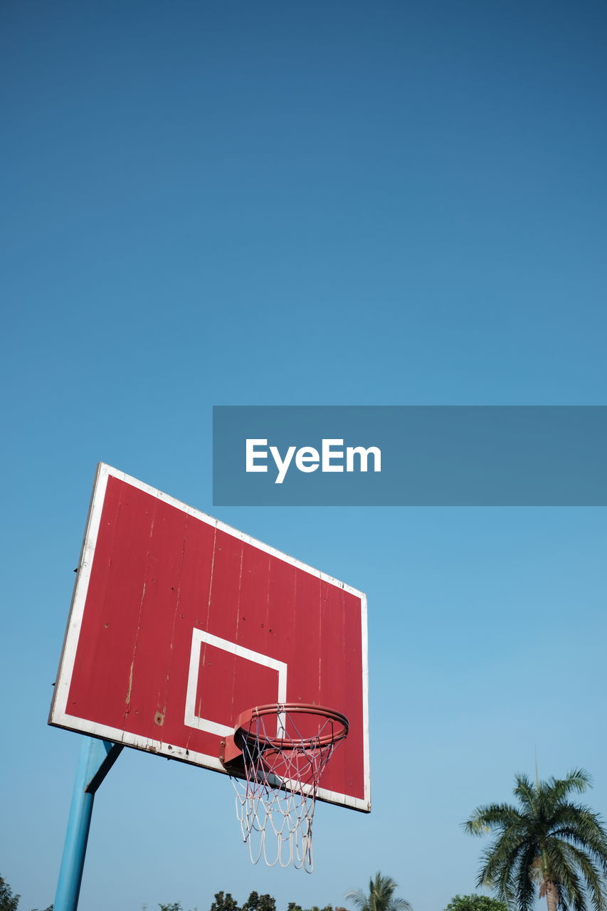Low angle view of basketball hoop against clear blue sky 