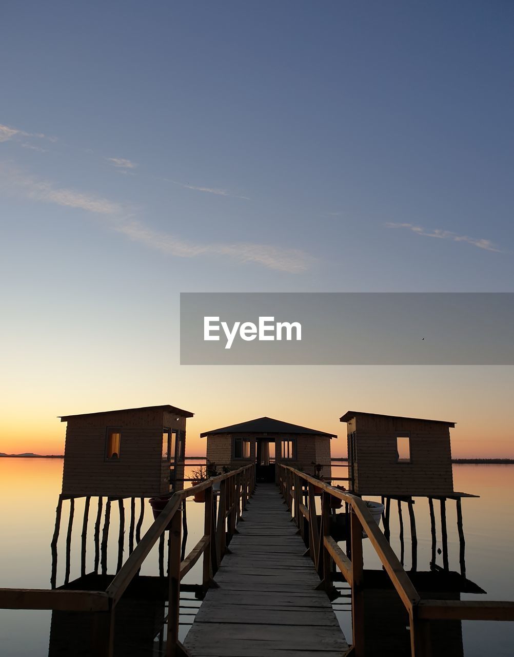 Pier over sea against sky during sunset