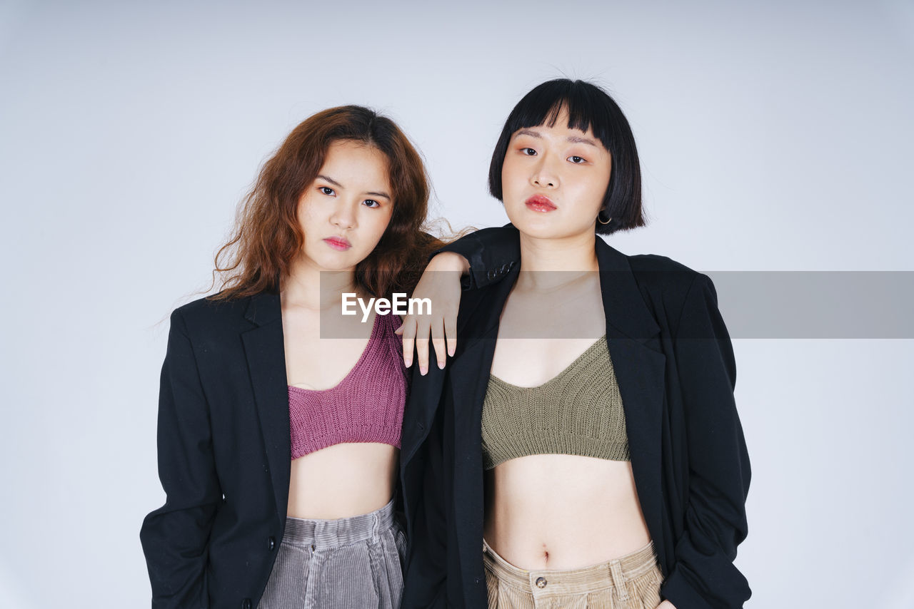 Portrait of lesbian couple wearing blazer against gray background