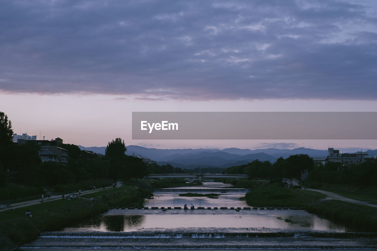 BRIDGE OVER RIVER AGAINST SKY AT SUNSET