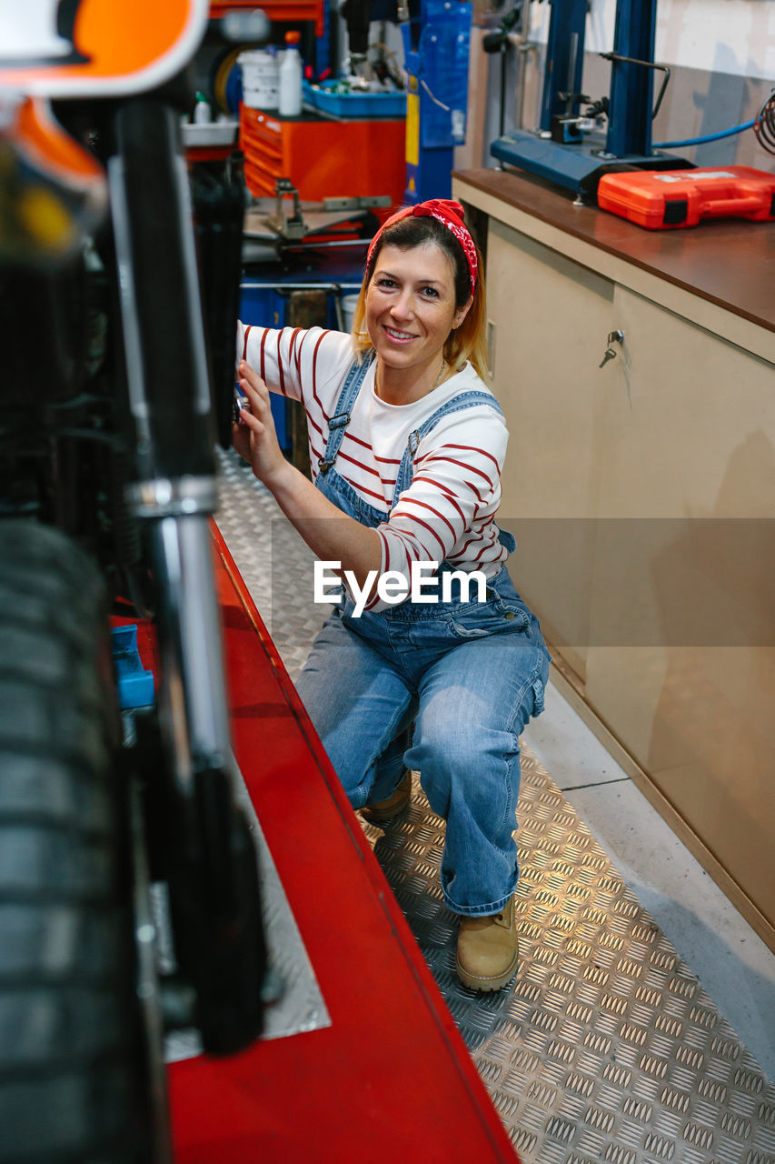 Portrait of mechanic woman repairing motorcycle on factory