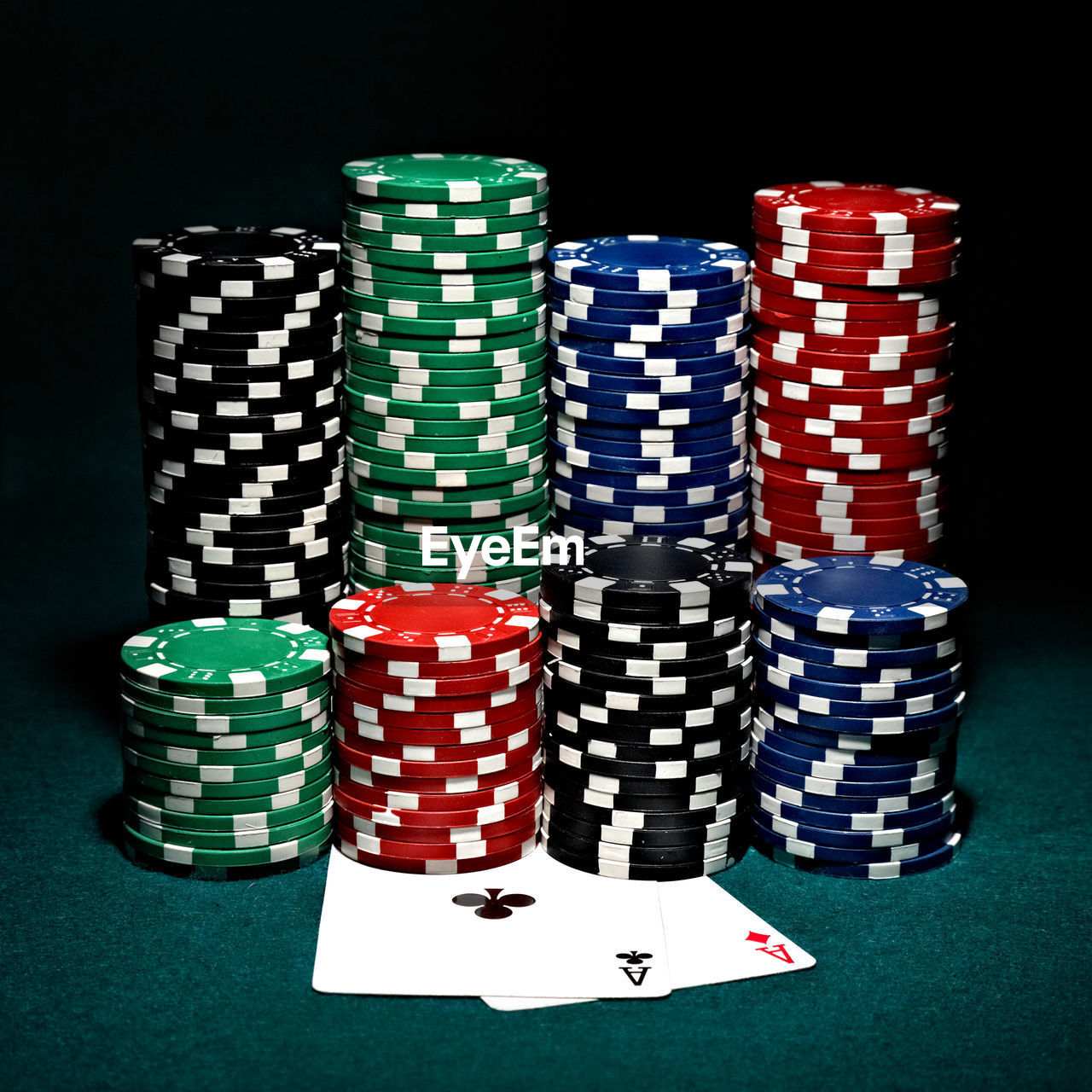 Stack of multi colored gambling chips on table against black background