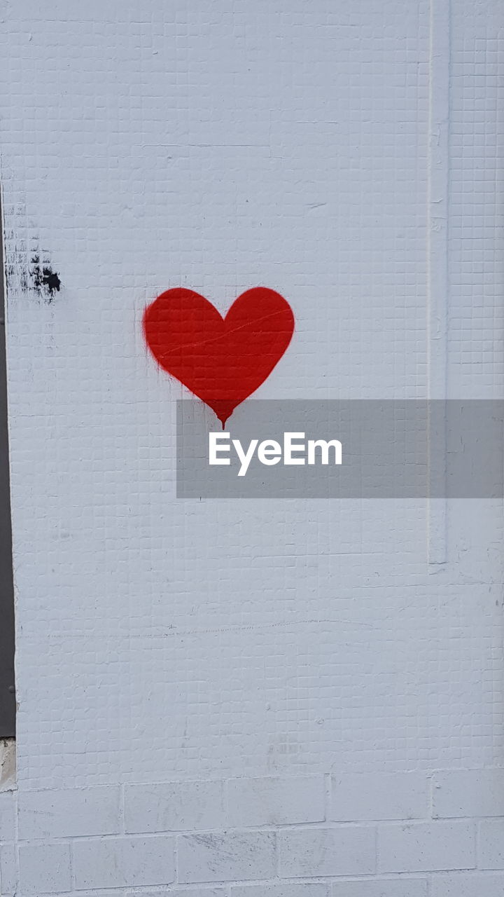 Red heart on a whiteboard wall with different bricks