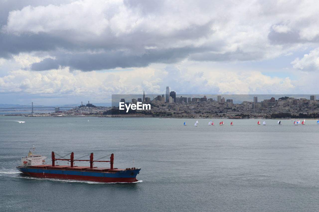 BOAT IN SEA AGAINST CITY BUILDINGS