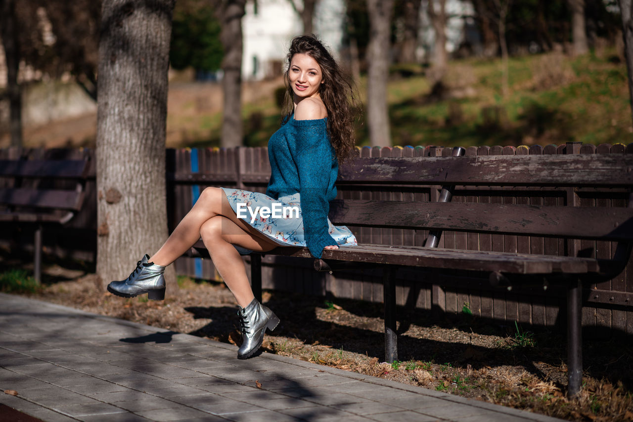 Portrait of woman sitting on bench in park