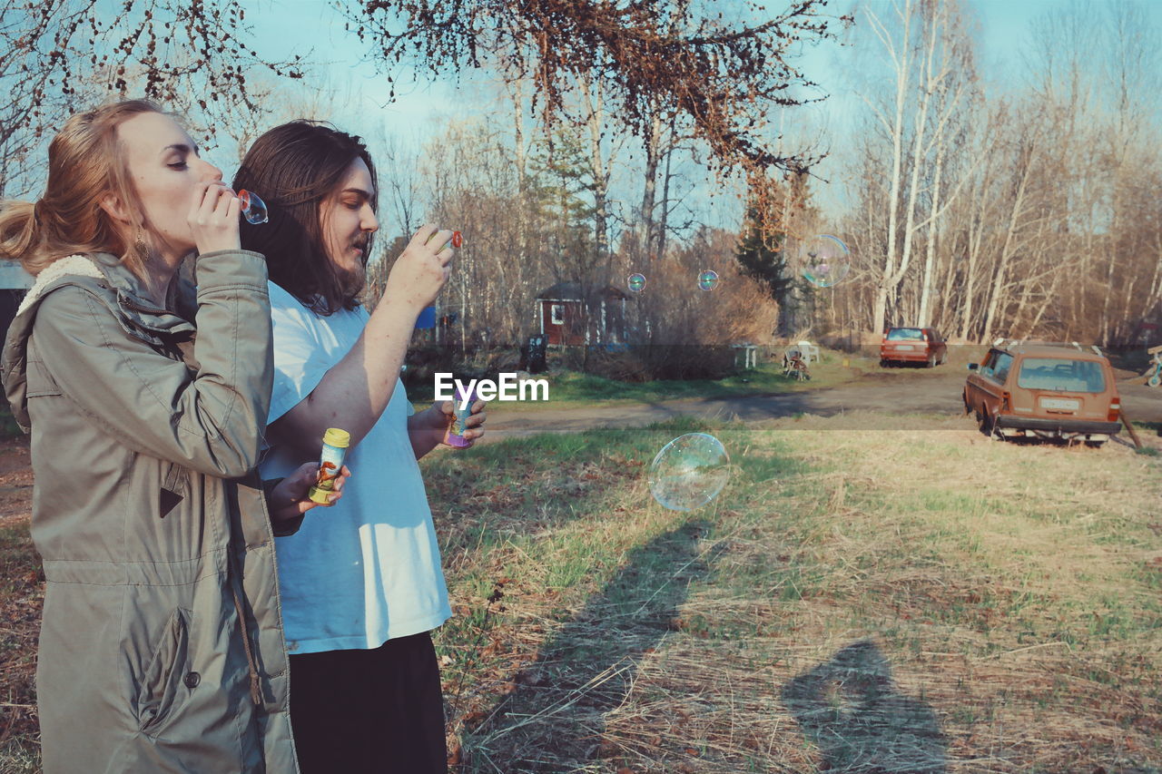 Women blowing bubbles on field