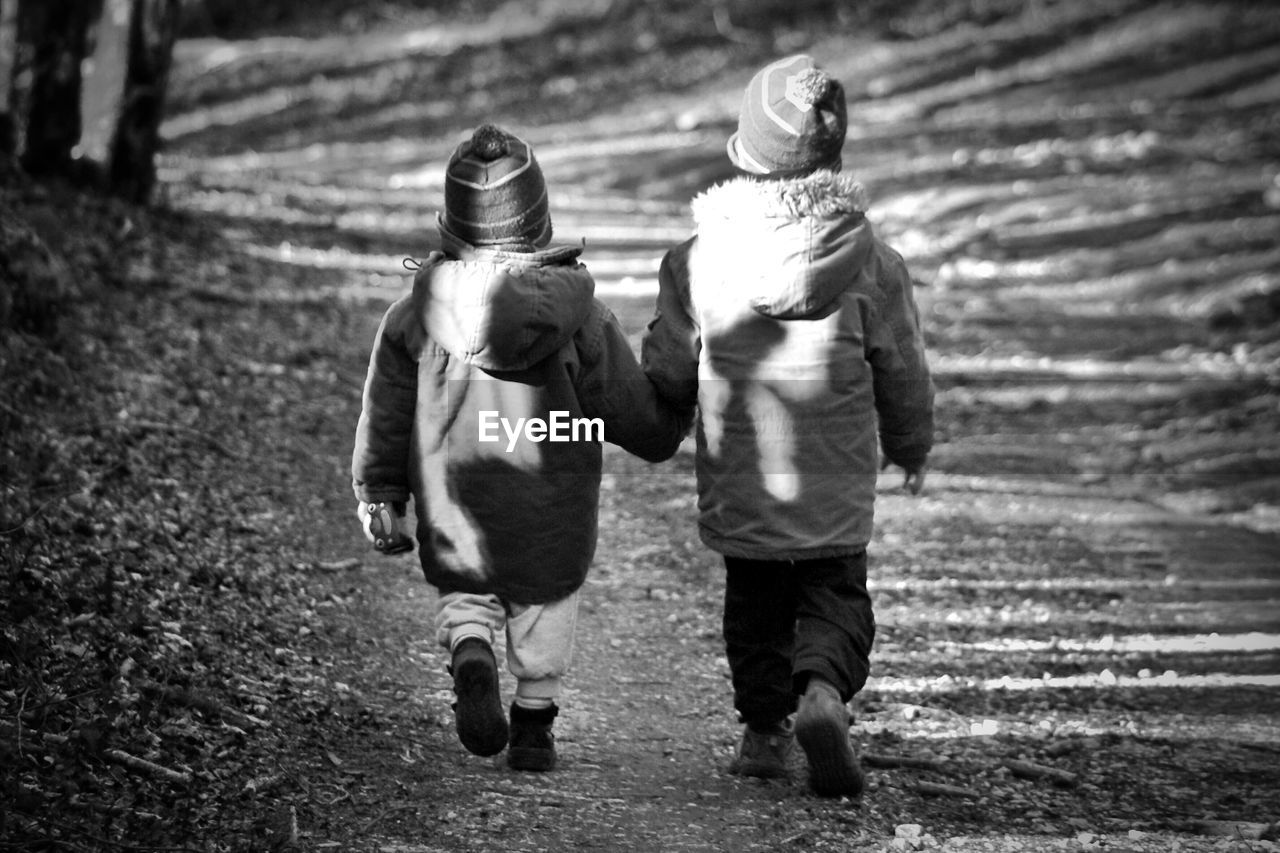 Rear view of boys walking on street