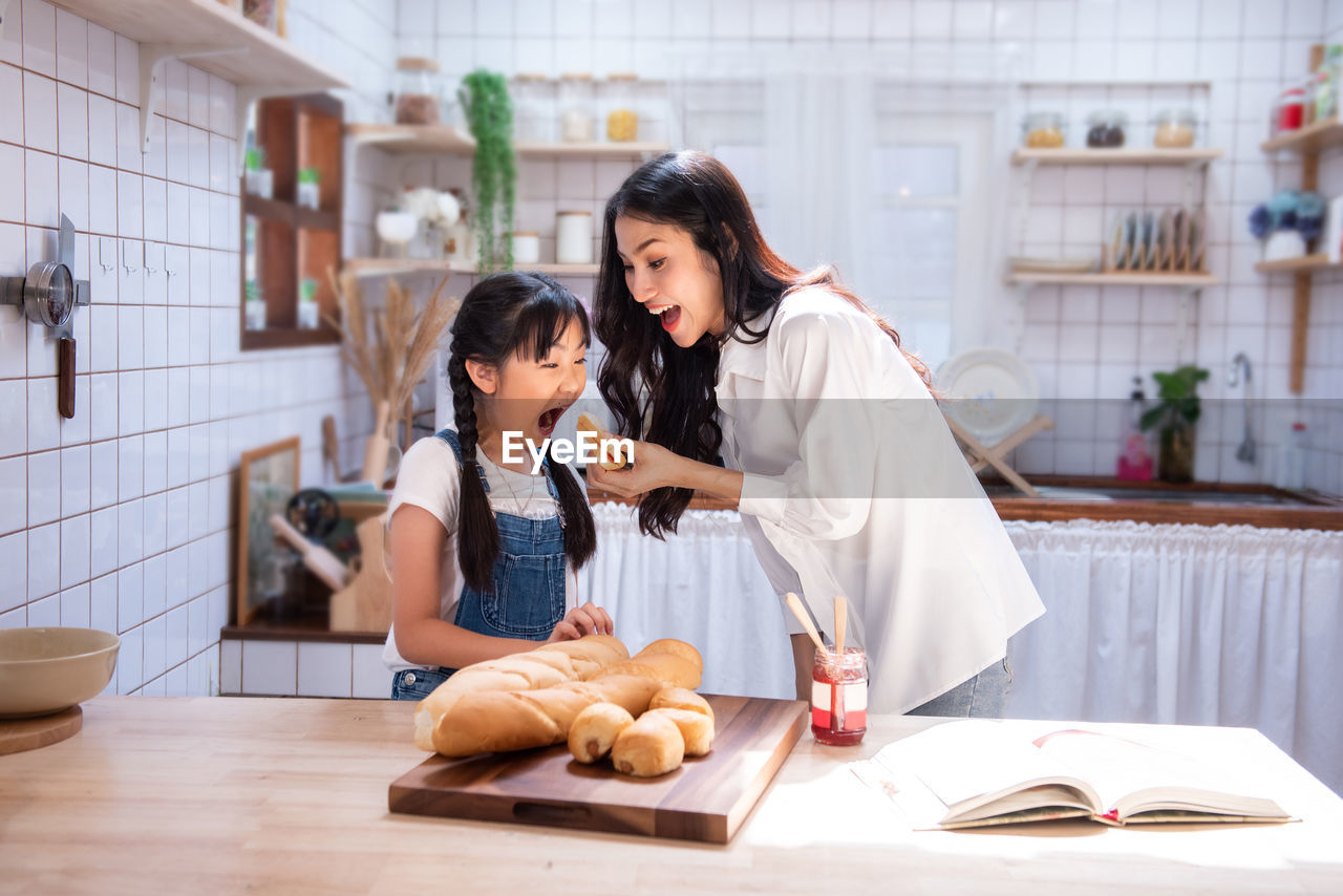 Happy family in the kitchen. asian mother and child daughter are having breakfast.