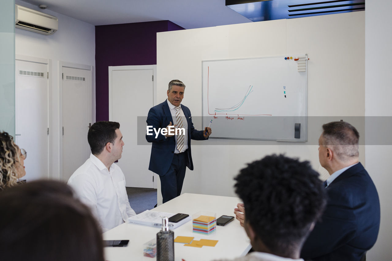 Mature businessman giving presentation in meeting at office