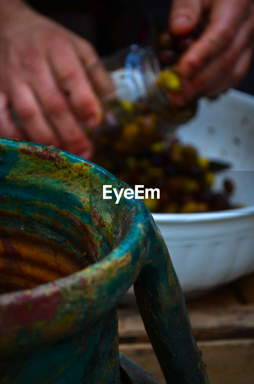 Cropped hands filling olive pickle in jar