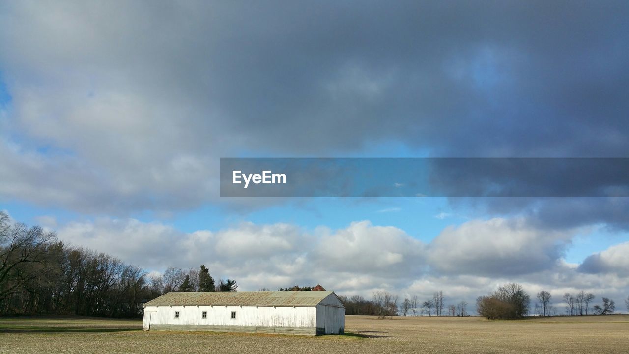 Barn on field against cloudy sky