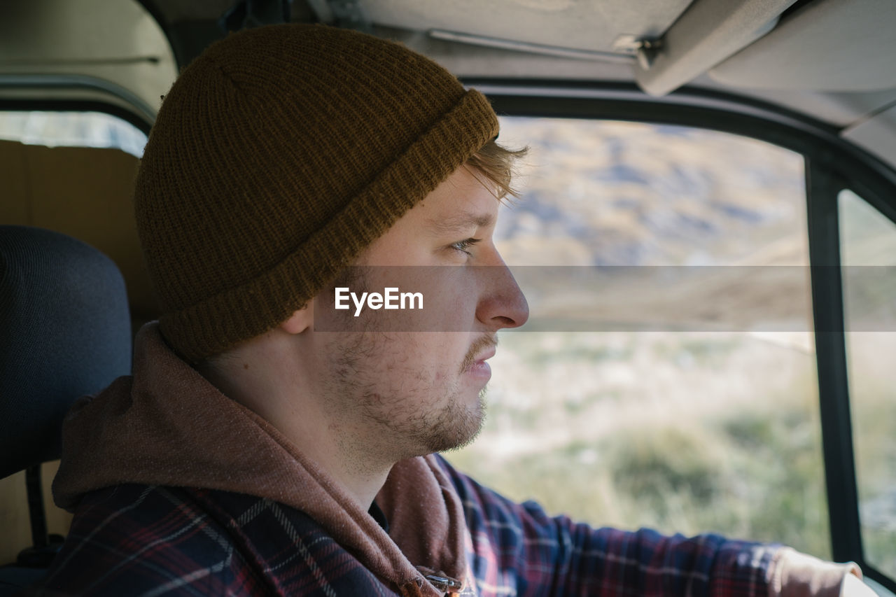 Side view of young man looking away while sitting in car