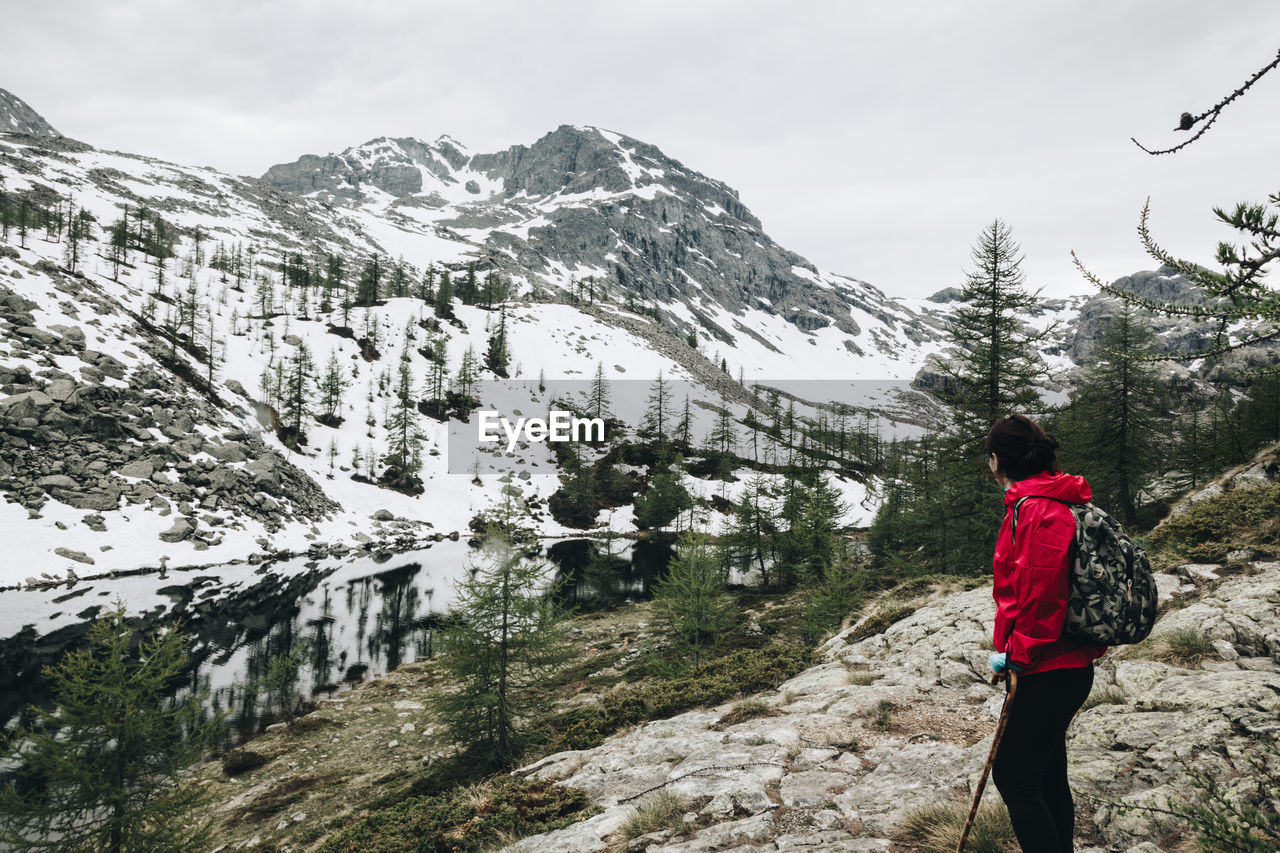 Hiker standing on landscape against snowcapped mountain