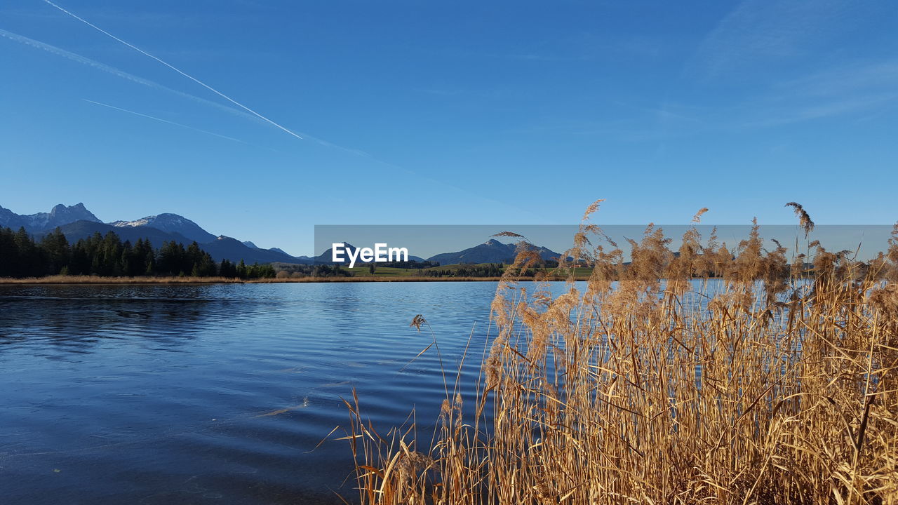 Scenic view of lake by mountains against blue sky