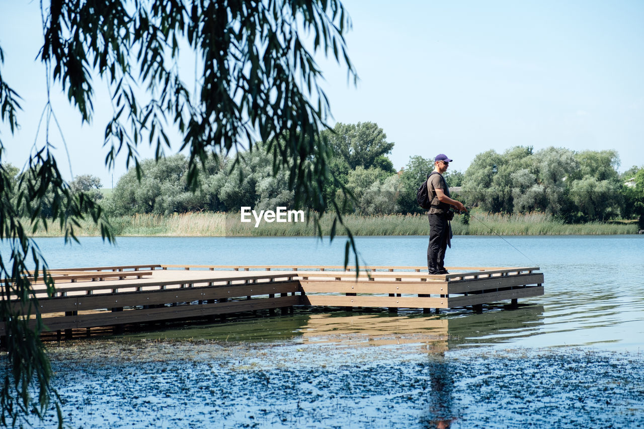 Fisherman with spinning rod on the lake. fisherman with spinning in his hands catching fish at sun