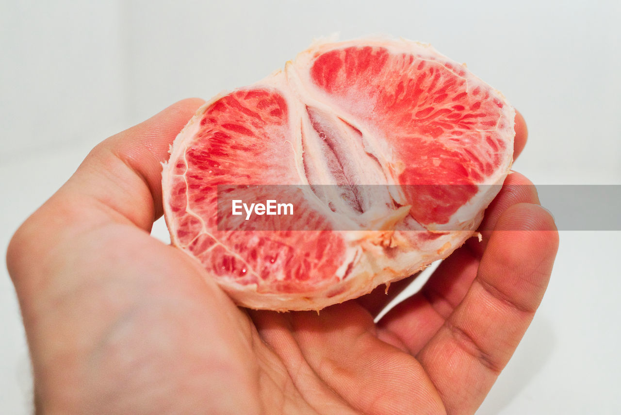 Close-up of hand holding half of a grapefruit