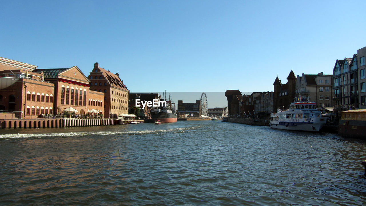 River amidst buildings against clear blue sky